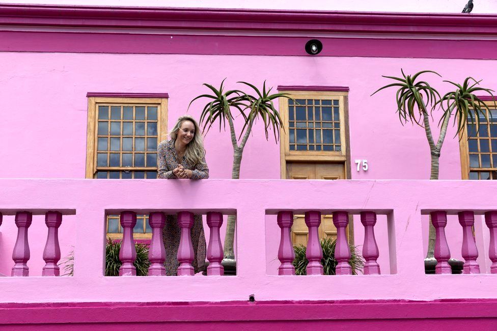 A tourist looks out from a balcony of a home in the Bo-Kaap neighborhood in Cape Town, South Africa, 30 October 2019. The Bo-Kaap Civic and Ratepayers Association has been awarded a gold certificate at the 2019 Simon van der Stel Awards for its efforts to preserve the heritage of their area. A one billion Rand development on the fringes of the Bo-Kaap was halted by residents in a clash with police in November last year. The Bo-Kaap neighborhood on Signal Hill dates back to the establishment of a Dutch colony on the Cape of Good Hope in the seventeenth century. It is a multi-ethnic and multi-lingual community composed of descendants from South and Southeast Asian nations who had been forcibly relocated to supply skilled labor for the expanding Cape Colony. The Bo-Kaap is recognized globally for its distinctive vernacular architecture and its enduring Muslim culture. The district preserves the largest collection of pre 1850 architecture in South Africa including the countries oldest mosq