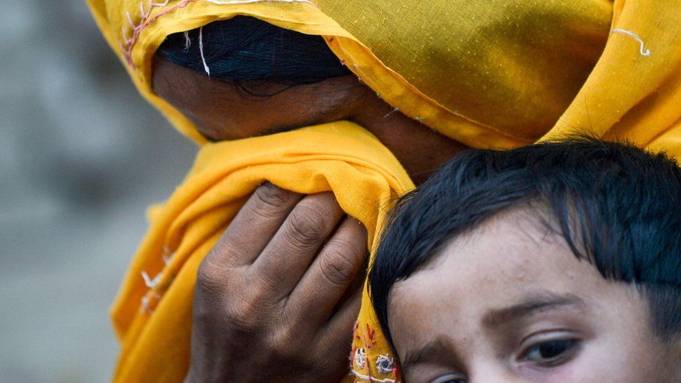 A woman holding a child, with her face in her hands