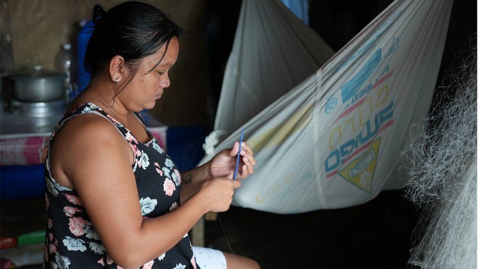 Женщина ремонтирует рыболовную сеть на острове Палаван, Филиппины