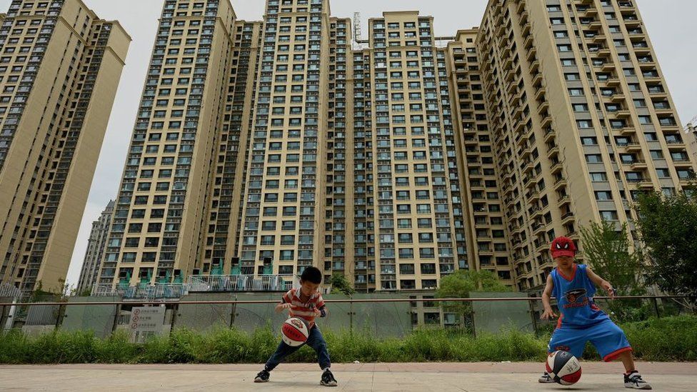 Children play basketball in front of a housing complex by Chinese property developer Evergrande.