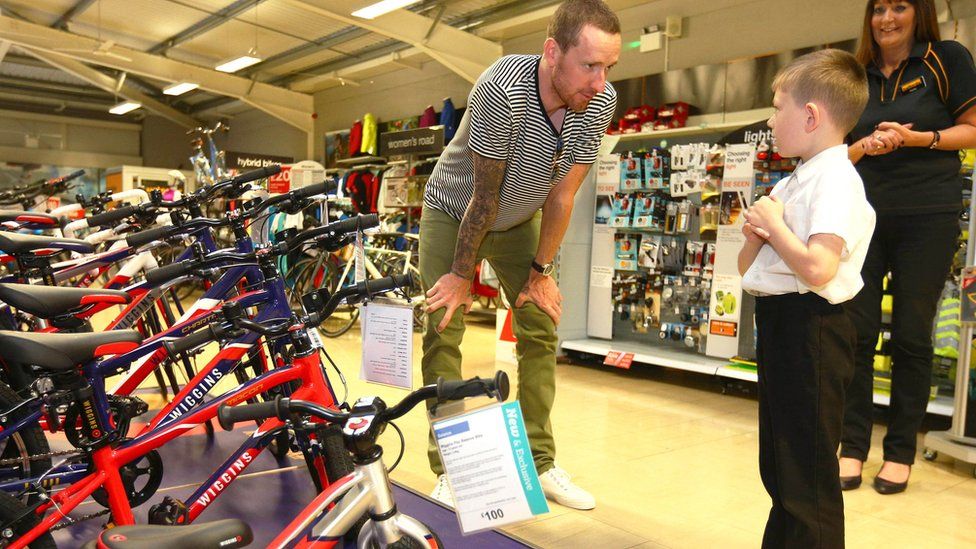 Sir Bradley Wiggins greets Lewis McEvoy, aged 7 from Blackley, at Halfords in Manchester as he visits the store to see his new exclusive range of children"s bikes