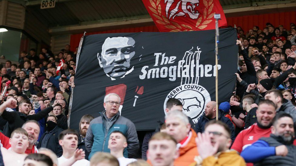 Fans holding a banner showing Steve Gibson as the "smogfather"