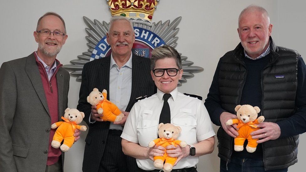 Police and charity officials holding teddy bears