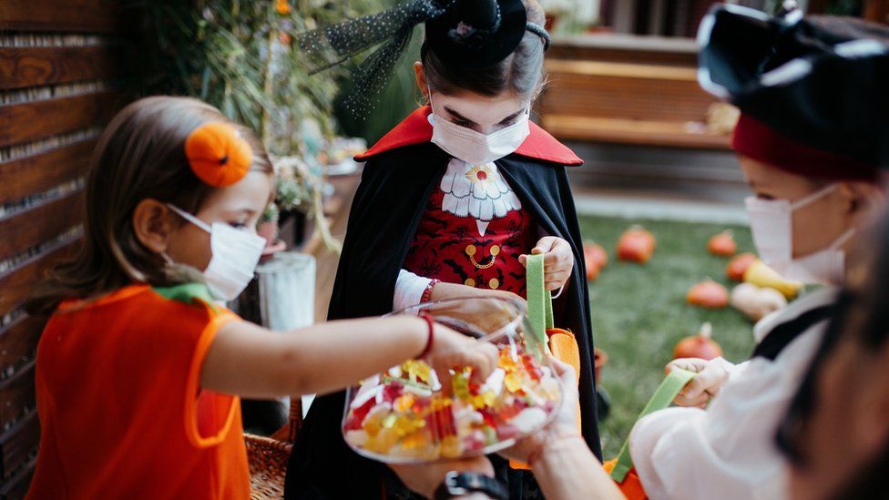 Children trick or treating while wearing masks