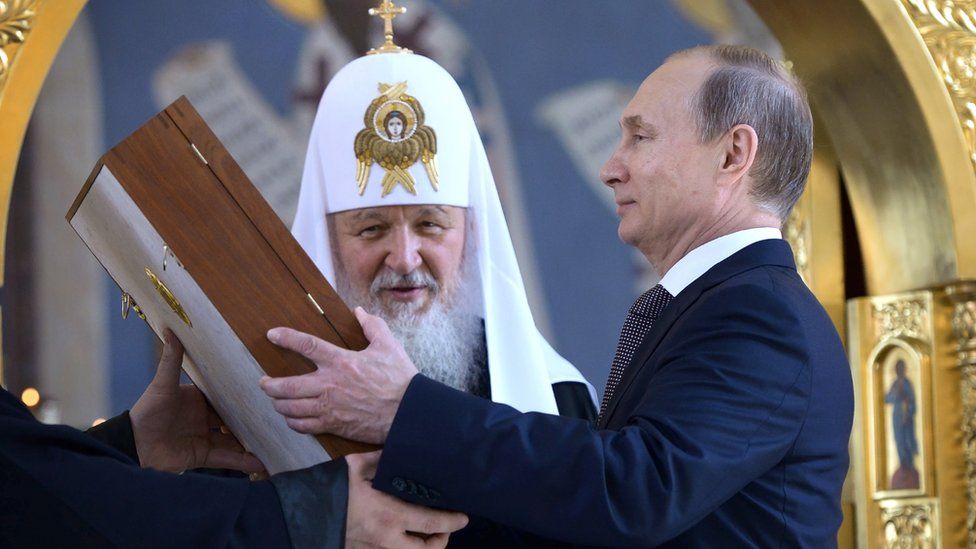 Russian President Vladimir Putin, right, looks at an icon while listening to Russian Orthodox Church Patriarch Kirill, 27 July 2015