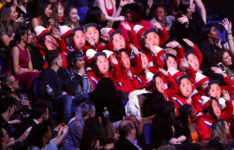 Spectators wear Kim Jong-un masks as they impersonate the North Korean cheerleaders.