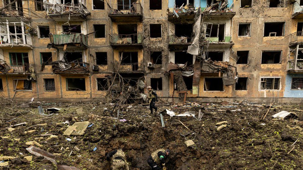 Ukrainian military personnel inspect the site of a missile strike in front of a damaged residential building, amid Russia's invasion, in Dobropillia, in the Donetsk region, Ukraine, April 30, 2022.