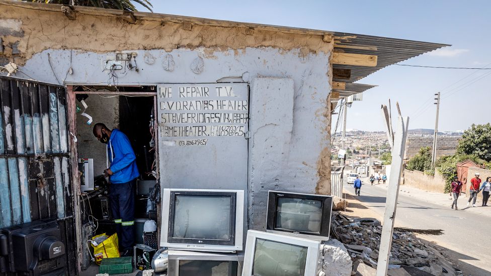Филимон Гветеквете работает в своей мастерской по ремонту телевизоров в поселке Александра, Йоханнесбург, Южная Африка
