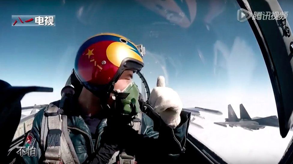 A pilot gives the thumbs-up to another plane, from the inside of his fighter jet's cockpit