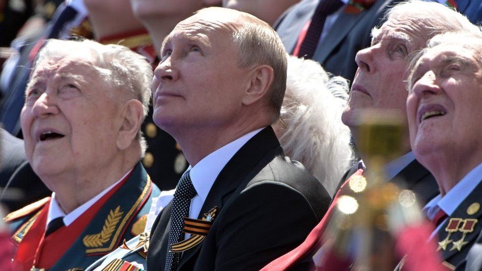 Vladimir Putin and veterans watching a military parade