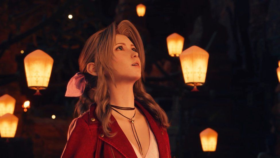 A young woman with long brown hair looks up in wonderment in this screenshot. It's a night-time scene, and the background is dotted with illuminated paper floating lanterns. The candlelight glow illuminates the woman, reflecting off her leather shoelace-style choker necklace and red jacket, creating a mystical feel in the scene. Her hair is tied back with a large, pink ribbon.