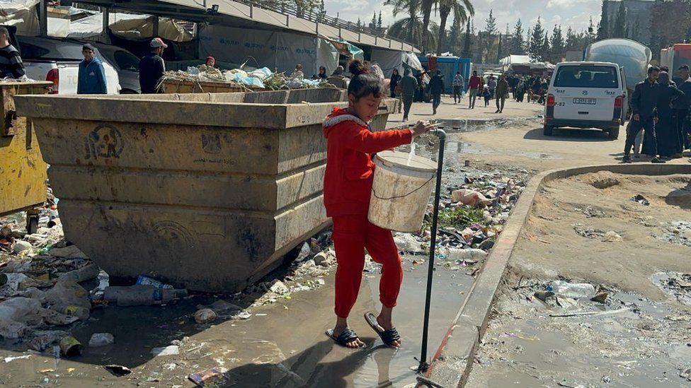 Girl filling up a bucket from a tap in Gaza