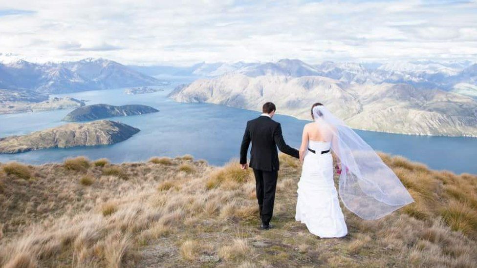 Kristy and Corey walk on the mountain top with a spectacular view of lakes and islands in front of them