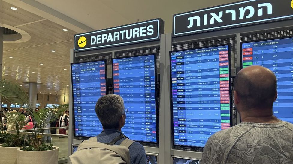 Люди рассматривают табло вылета в аэропорту Бен-Гурион