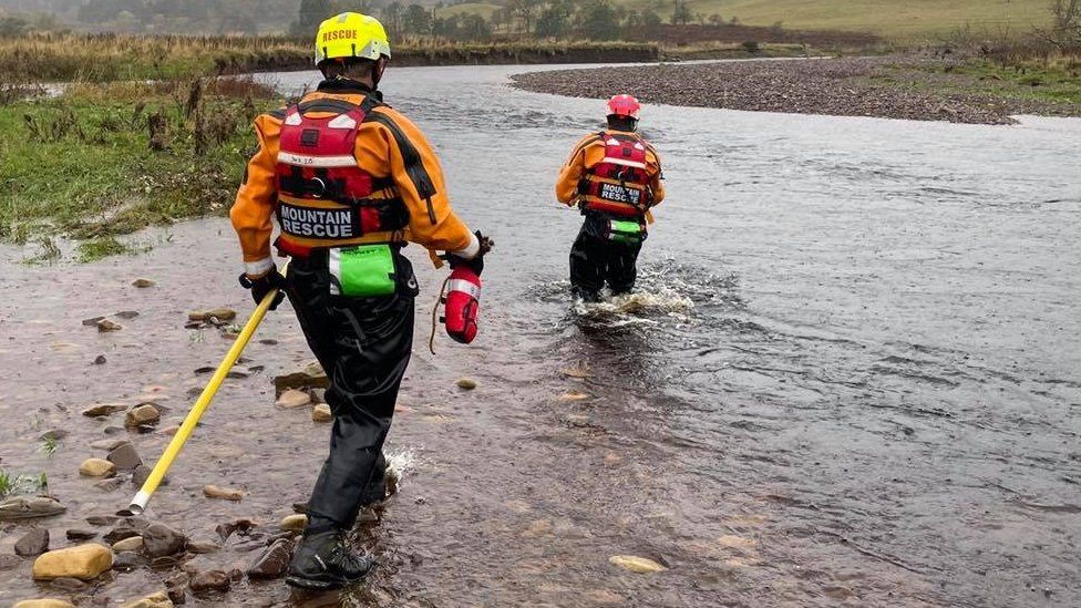 Two rescuers enter the river