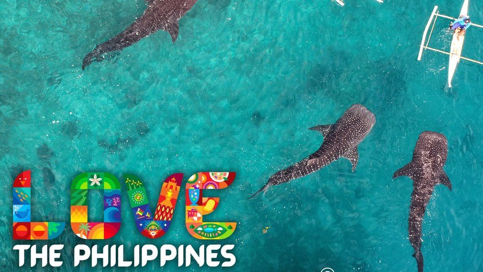 Фото со слоганом 'Любите Филиппины' на картинке с китовыми акулами возле байдарочников