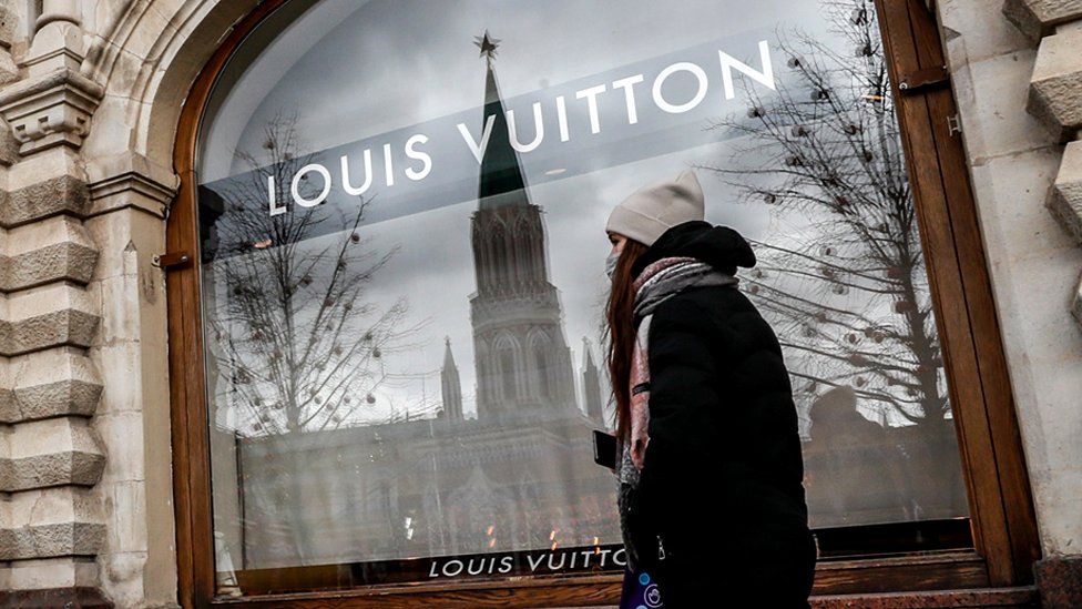 A woman walks near the window of a closed Louis Vuitton shop in Moscow, on 7 March 2022