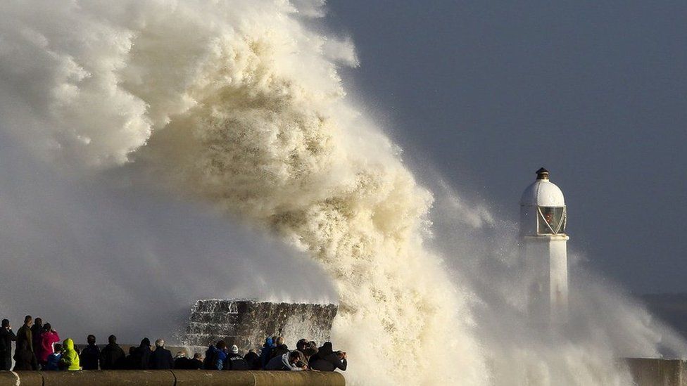 Huge waves crashing into barriers near a lighthouse