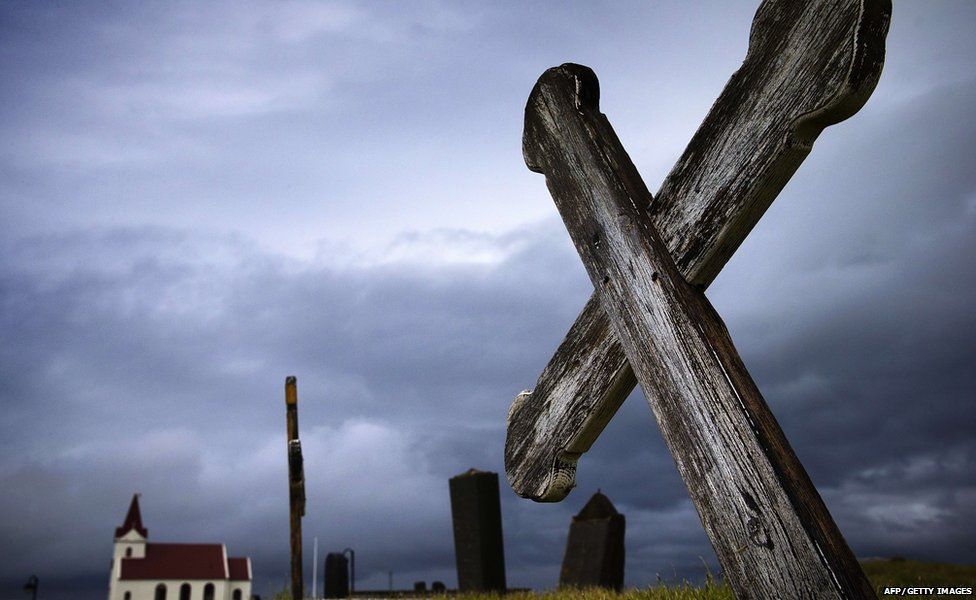This picture taken on July 10, 2014 shows a cross in the cemetery and the church of Kjalvegur, southwest Iceland.