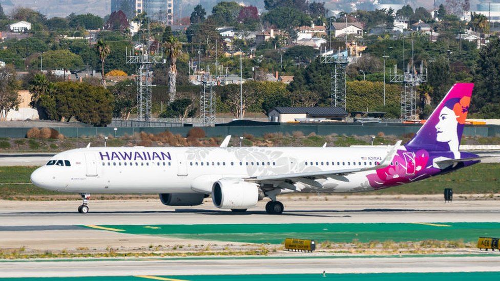 A Hawaiian Airlines plane sits on the tarmac