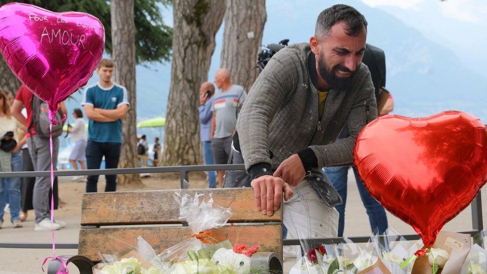 Salih Ismajl cries in front of messages and floral tributes in Annecy
