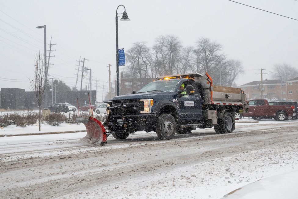 : A snow plough passes as heavy snowfall begins in a western suburb of Chicago as a winter storm arrives in the Midwest.