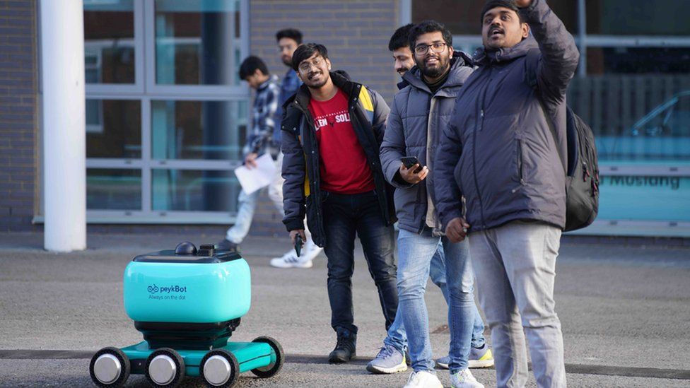 Students standing by a robot and taking a selfie