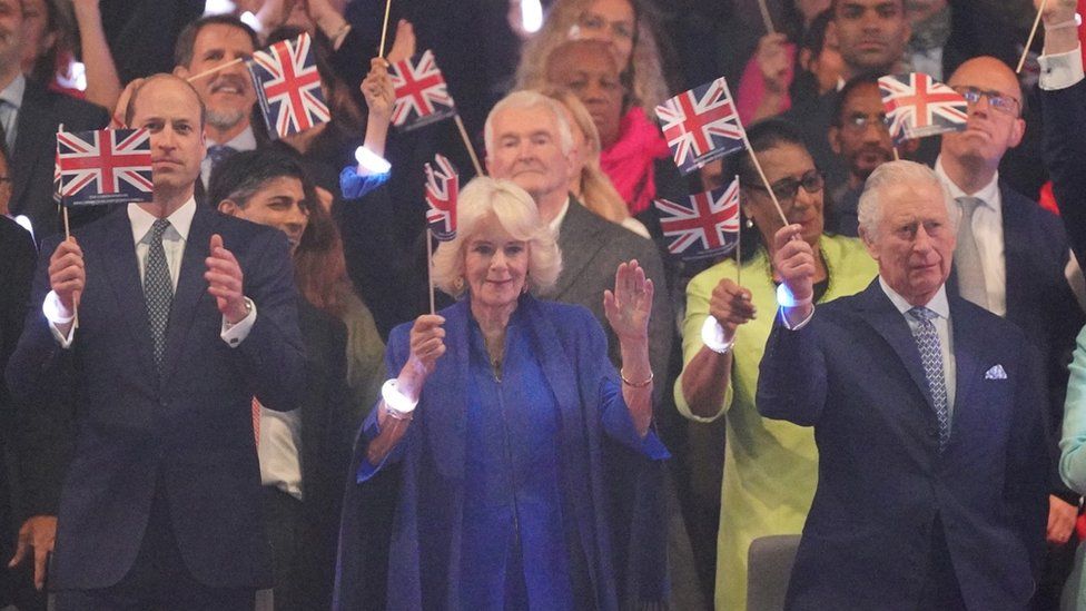 The Prince of Wales (L), the Queen and the King (R) wave flags at the concert on Sunday