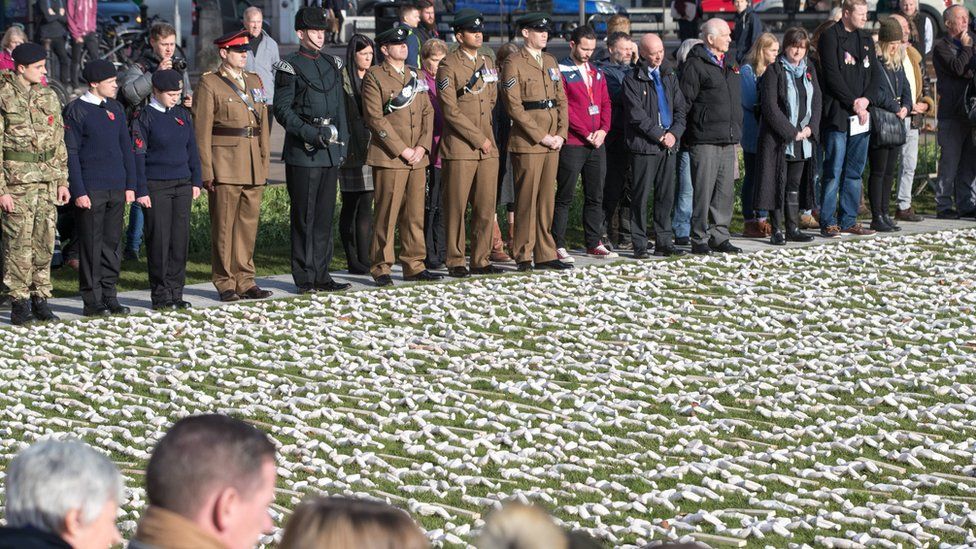 People gather around the 19,240 figurines that have been laid out on College Green, Bristol