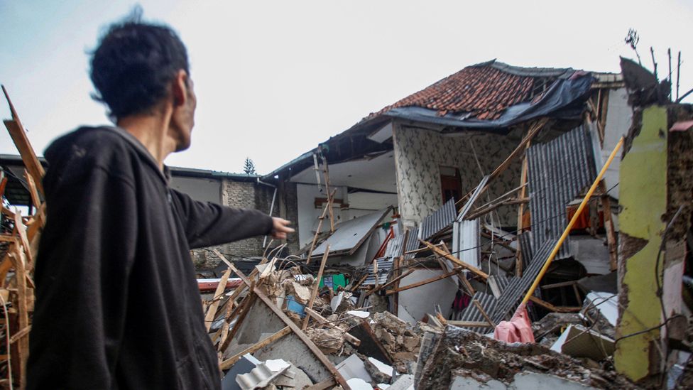 A man stands near houses damaged after earthquake hit in Cianjur, West Java province, Indonesia