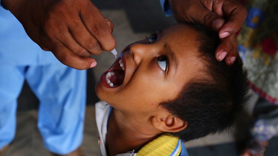 A health worker gives the polio vaccine to a child in Pakistan