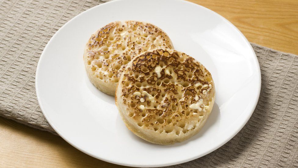Two buttery crumpets on a white plate
