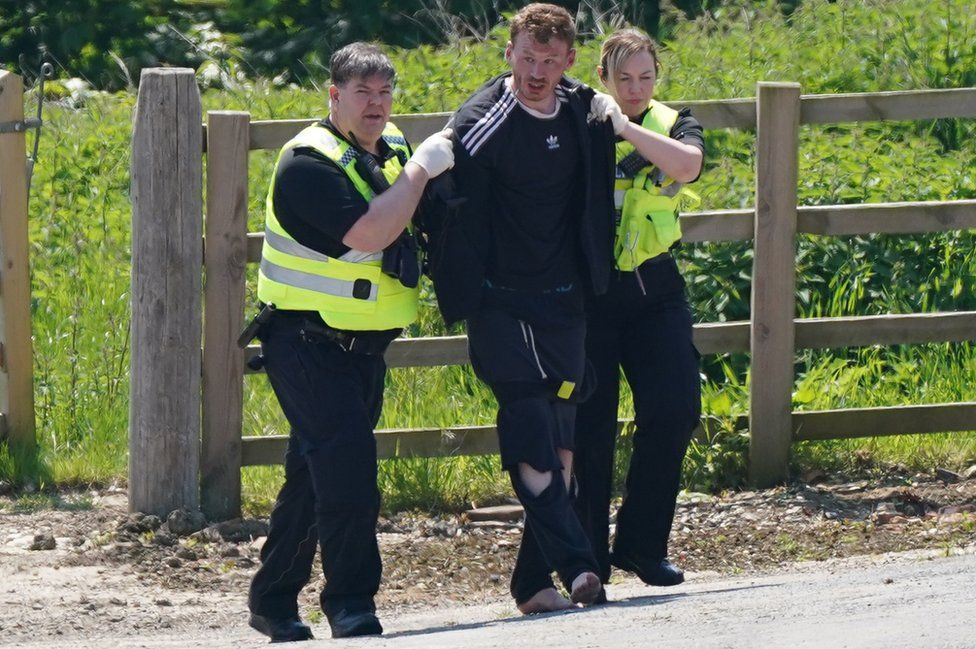 Two officers escort Daniel Boulton to a police van