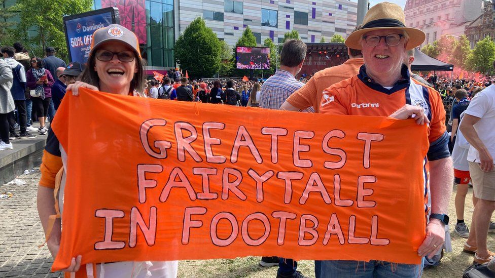 Joanne Stuckey and Tim Hayden holding up a "Greatest Fairy-tale In Football sign"