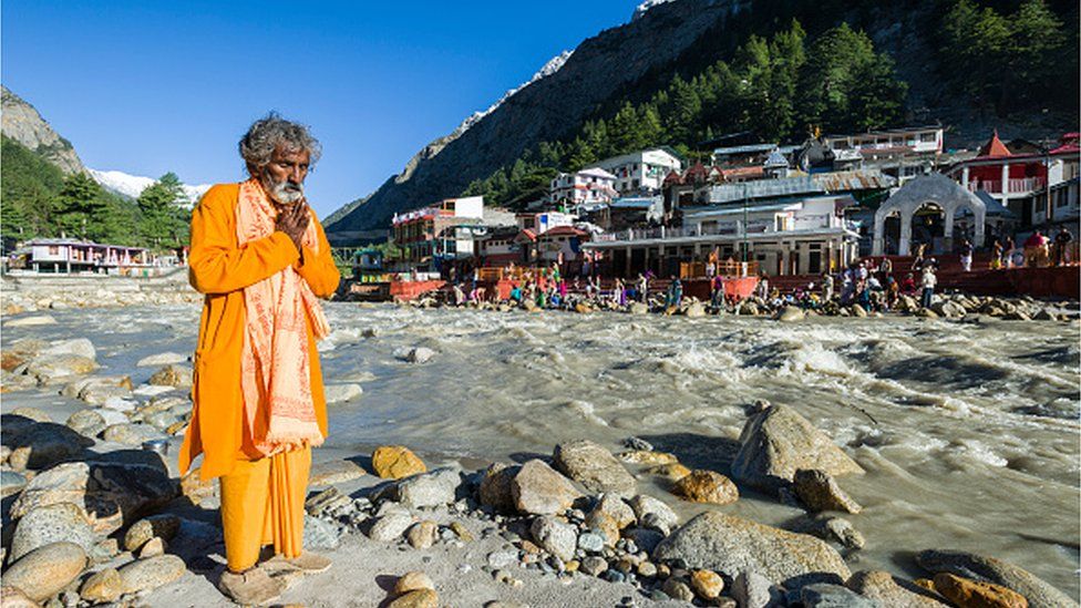GANGOTRI, UTTARAKHAND, INDIA - 2015/05/27: The very important pilgrimage place for Hindus and Buddhists is located at the young river Ganges and part of the Chota Char Dham, a devotee is praying at the waterfront