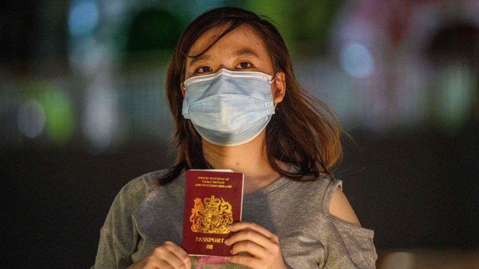 A young woman holds a BNO passport