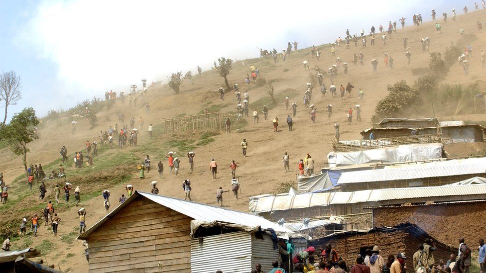 A file picture taken on May 28, 2013 shows people carrying bags of cassiterite (tin ore), coltan, which is used in mobile telephones and computers, and manganese down a hill from the Mudere mine, near Rubaya