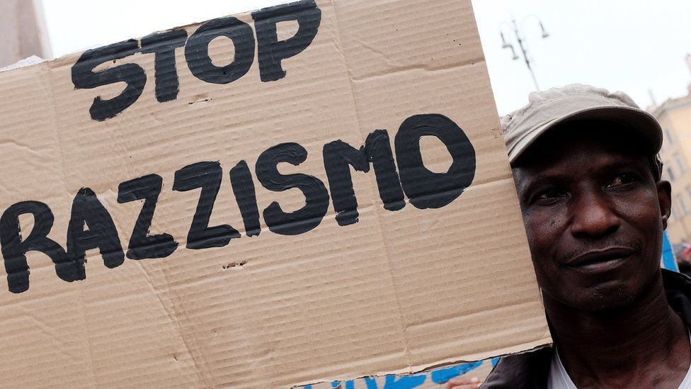 A migrant holds a placard reading 'stop racism' during a demonstration in Rome on 16 June, 2015