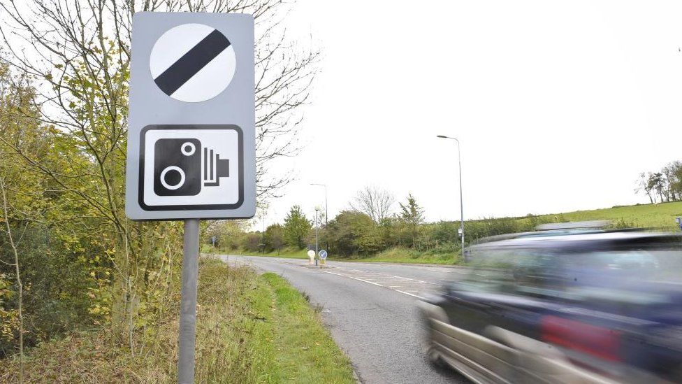 National speed limit sign with car (distorted by motion blur) speeds by on country road