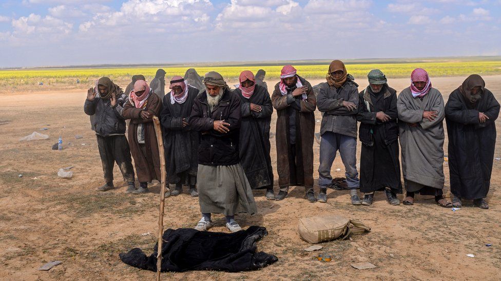 Men suspected of being Islamic State group's members pray at a screening area held by the US-backed Kurdish-led Syrian Democratic Forces (SDF), after they fled the embattled IS holdout of Baghouz in the eastern Syrian province of Deir Ezzor, on March 6, 2019