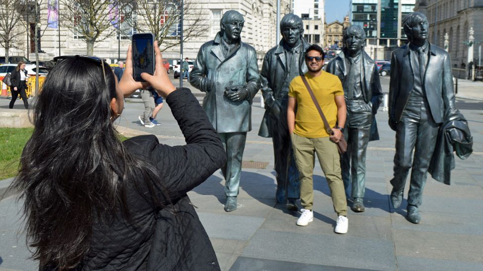 Туристы фотографируются у статуи Битлз в Ливерпуле, 18 апреля 2023 г.