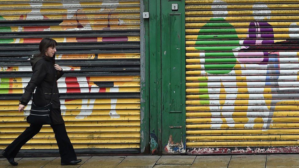 A woman walks past shop shutters in Sunderland