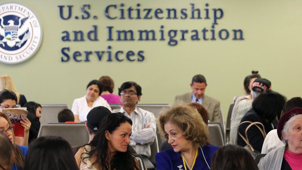 Women in front of a sign for US citizenship and immigration services