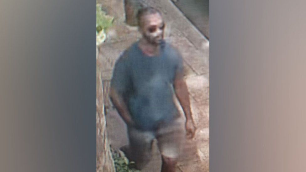 CCTV footage shows a black man in a dark grey shirt and light coloured shorts. He is also wearing sunglasses.