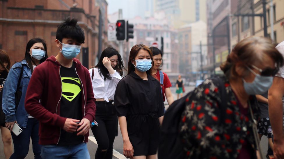 People wear face masks while walking through Sydney