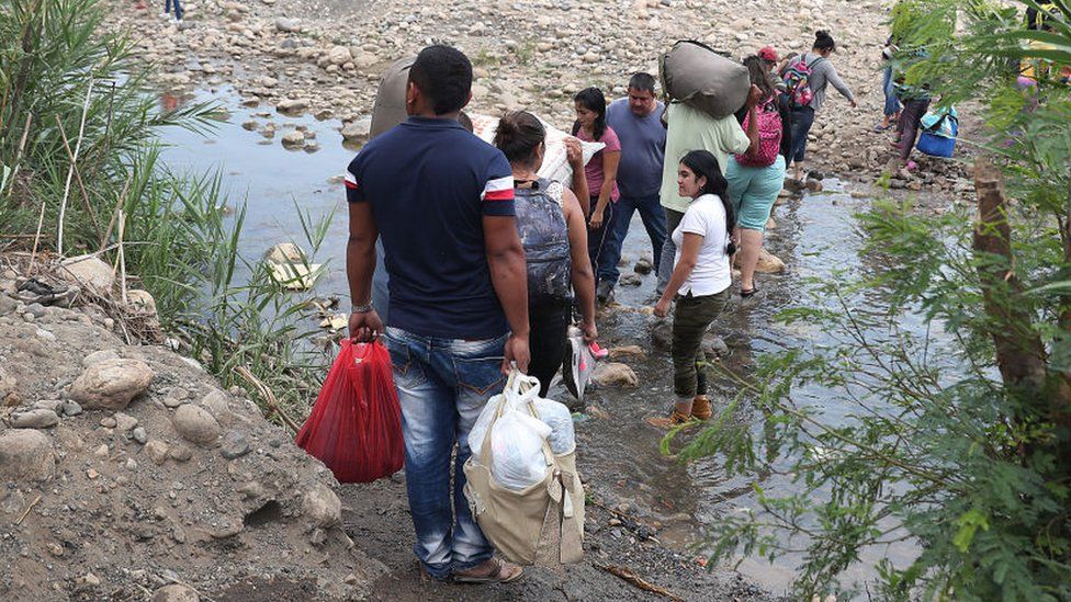 People cross through the low waters of the Táchira River near the Simón Bolívar international bridge, which connects Cúcuta with the Venezuelan town of San Antonio del Táchira, after the closure of the border bridge on February 27, 2019 in Cucuta, Colombia.