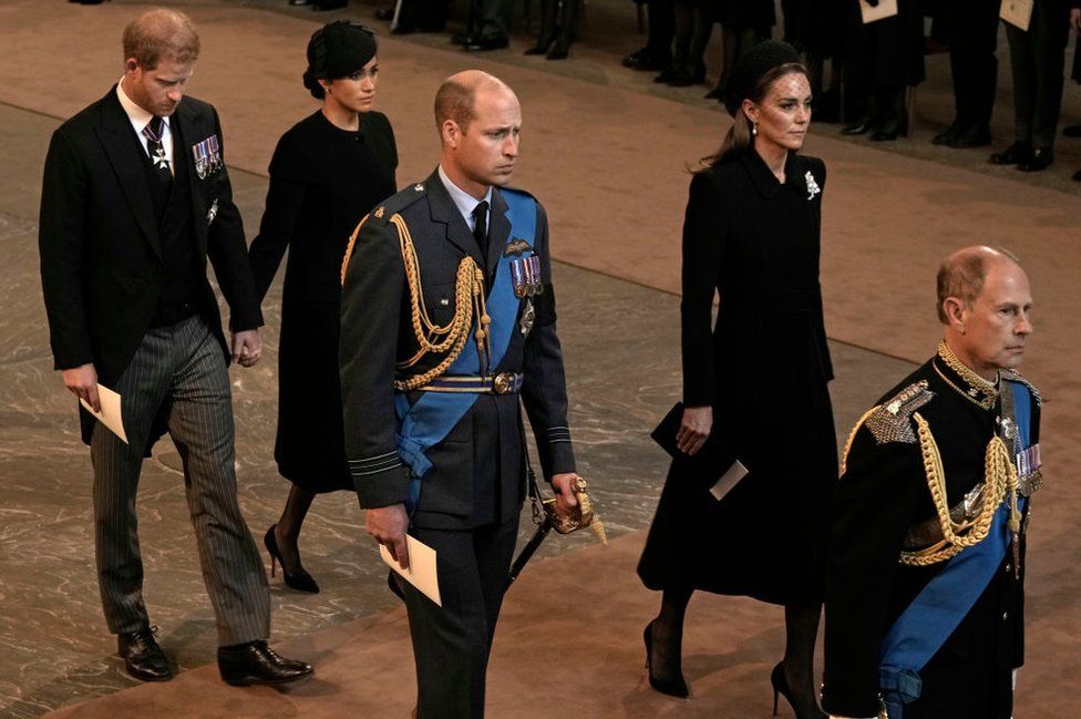 The Duke and Duchess of Sussex hold hands as they walk in Westminster Hall, with the Prince and Princess of Wales and Prince Edward ahead of them