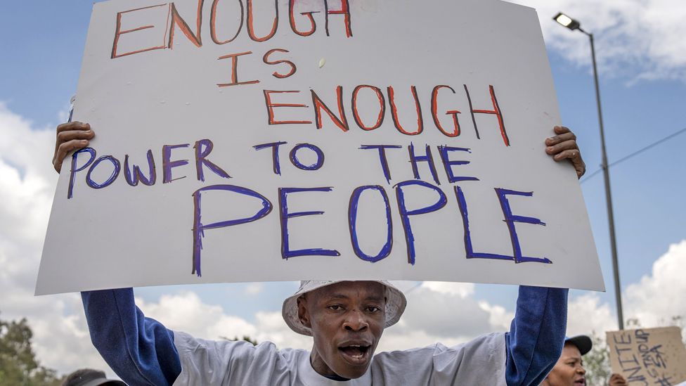 Люди с транспарантами устраивают акцию протеста против энергетического кризиса после длительных отключений электричества в Йоханнесбурге, ЮАР - 2023