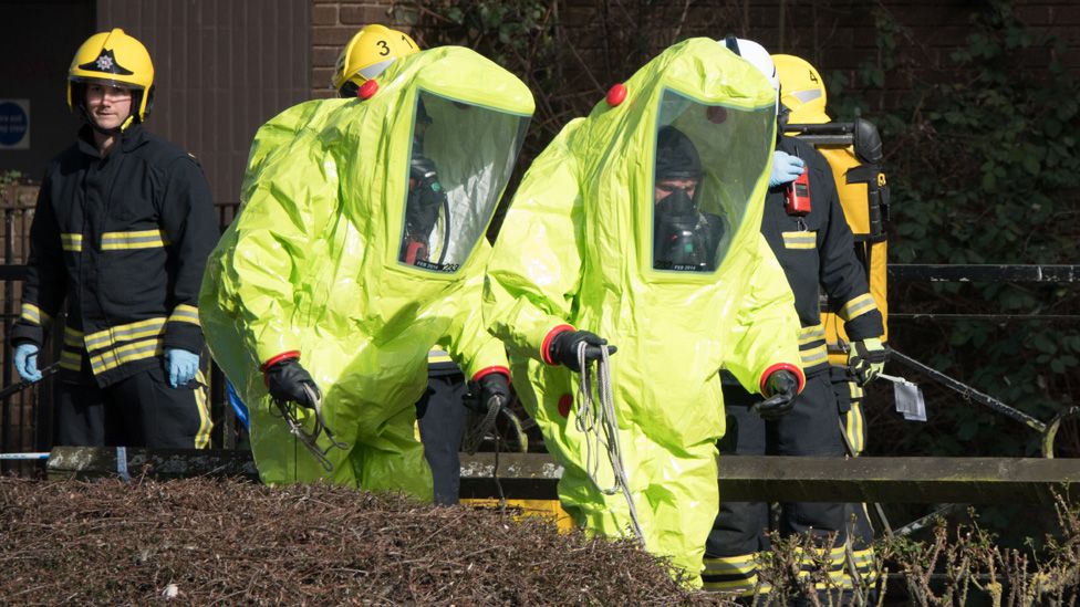 Specialist officers in protective suits prepare to secure the police forensic tent that had been blown over by the wind and is covering the bench where Sergei Skripal was found critically with his daughter on March 4