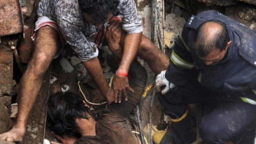 Rescue workers pull out a victim from the rubble at the site of a collapsed building in Mumbai